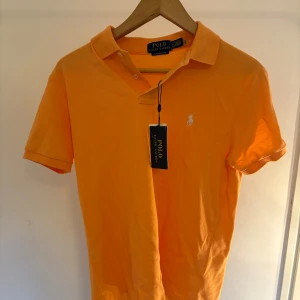 Orange Ralph Lauren piketröja - Orange Ralph Lauren piketröja, aldrig använd tags sitter kvar. Kvitto finns för äktehets verifiering. Priset ej fast vid snabb affär. Ny pris 1499 kr, mitt pris 900 kr. Ställ gärna frågor innan ni köper. 
