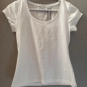 Vit t-shirt från Kappahl - En klassisk vit t-shirt från Kappahl med rund halsringning och korta ärmar. Tillverkad i mjuk bomull och har en enkel, stilren design som passar till det mesta. Perfekt basplagg i garderoben. Jag säljer tröjan då jag helt glömde bort att lämna tillbaka den inom 30 dagar. Nypris-179kr