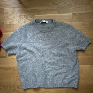 Grå stickad kortärmad tröja från Zara - Mysig grå stickad tröja från Zara med korta ärmar och rund halsringning. Perfekt för lager-på-lager och enkel att matcha med olika outfits. Ribbstickade detaljer vid ärmslut, hals och nederkant. Pris kan diskuteras. Storlek L men jag skulle säga att den sitter mer som M. Har nästan inte använts alls så den är i nyskick. Skriv om du har frågor 💕.