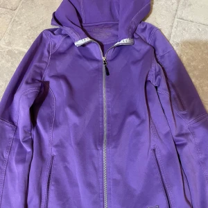 Lila hoodiejacka med dragkedja - Säljer en lila hoodiejacka med dragkedja framtill och huva. Jackan har långa ärmar och två fickor med dragkedja. Perfekt för vår eller höst och passar till en avslappnad stil. Perfekt till träning 