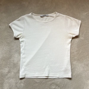 Vit ribbad t-shirt från Lager 157 - Säljer en enkel och stilren vit ribbad t-shirt från 157. T-shirten har korta ärmar och rund halsringning, perfekt för en clean och avslappnad look. Passar till det mesta och är superbekväm att bära.