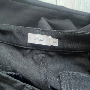 Svarta kostymbyxor från Nelly - Snygga svarta lågmidjade kostymbyxor från Nelly med klassisk rak passform. Byxorna har pressveck och två fickor bak. Säljer dom då de inte passar mig längre,de är i väldigt bra skick då jag använt dom 2 gånger.
