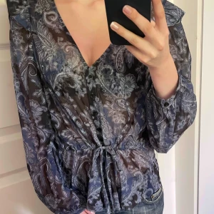 Marinblå blus med vacker design från ellos - Säljer denna snygga marinblå blus med fina detaljer från ellos, det finns ett snöre vid midjan för en bra passform. Använd ett fåtal gånger.