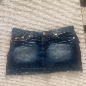 Jeanskjol från Victoria Beckham x Rock & Republic - Säljer en snygg jeanskjol i klassisk blå denim med slitna detaljer och fina fickor. Köpt second hand, svår att få tag på. Stolek 31 , ungefär M 