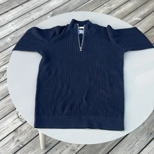 Mörkblå stickad tröja med dragkedja från Jack & Jones - Mörkblå stickad tröja från Jack & Jones med halv dragkedja framtill och ståkrage.. Perfekt för våren/ sommaren. Använd en två gånger. Ny pris 399kr mitt pris 179kr men pris går att diskutera. Passar ca 155 cm.