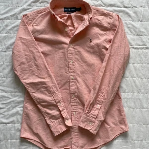 Ralph lauren skjorta - Säljer denna skitfeta aprikosfärgade ralph lauren skjorta! | Skjortan är i storlek S custom fit. | Perfekt för sommaren då den verkligen tar fram solbrännan och automatiskt gör dig brunare. | Släng iväg en signal vid funderingar så svarar jag snabbt. |