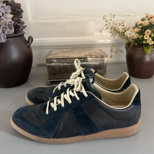 Maison Margiela  - Säljer nu mina Maison Marigiela i marinblå storlek 43. Säljer eftersom det börjar bli för små för mig jag har haft de i 4 månader ungefär och känner att det är dags att sälja dem nu. Skorna är använda varsamt och kräva bara en tvätt för att få dom att se nya ut. Skolåda & dustbag kommer med vid köp. Priset är inte hugget i sten och kan sänkas vid snabb affär! 