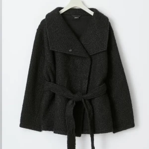 Svart kort kappa - Säljer denna korta kappan från gina tricot, den är helt oanvänd och säljer då jag inte får någon användning för den. Skriv vid fler frågor!🩷