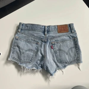 Ljusblå jeansshorts med fransar från Levi's - Säljer ett par ljusblå jeansshorts från Levi's med råa fransade kanter och klassiska bakfickor. Använda 3 gånger 💗
