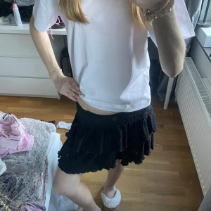 Svart volangkjol - Säljer en svart kortkjol med flera volanger. Kjolen har en elastisk midja, perfekt till sommaren!