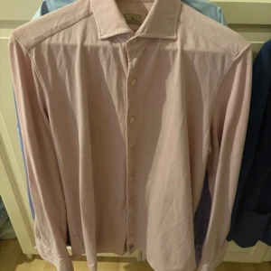 Ljusrosa skjorta från Sonrisa - Säljer en stilren ljusrosa skjorta från Sonrisa i storlek M. Skjortan har klassisk krage, knäppning framtill och långa ärmar med manschett och knapp. Perfekt för dig som gillar en clean och tidlös look. Nypris 2500