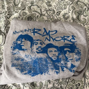 Grå hoodie med blått Mount Rapmore-tryck - Säljer en grå hoodie med blått tryck av fyra rappare och texten 'Mount Rapmore' på bröstet. Hoodien har klassisk passform och huva. Perfekt för dig som gillar streetwear och hiphop.