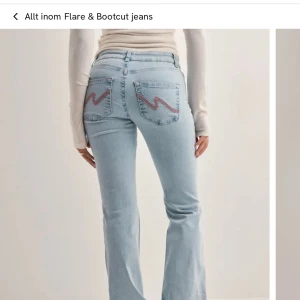 Bootcut jeans i ljusblå denim med broderade bakfickor - Säljer ett par ljusblå bootcut jeans med snygga broderade detaljer i rosa på bakfickorna. Jeansen har låg midja. Kom privat för bilder på dem💕