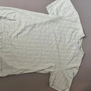 Beige och grön  randig t-shirt från Karl Kani - 2 st T-shirts från Karl Kani med tunna vita ränder och broderad logga på bröstet. T-shirten har rund hals och är kortärmad. 