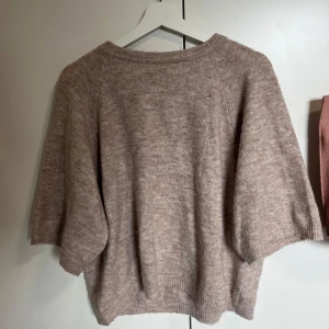 Beige stickad tröja med kort ärm - Mysig beige stickad tröja med korta ärmar och rund hals. Tröjan har en avslappnad passform och är perfekt för lager-på-lager. Passar bra till både jeans och kjol. Trendig just nu