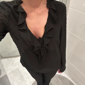 Blusar  - Säljer en svart v ringad blus med v ringning, den har slits i armarna och knyte vid bröstet. Storlek 36.