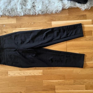 Svarta kostymbyxor med hög midja - Säljer ett par svarta kostymbyxor med hög midja och raka ben från Zara . Byxorna har diskreta fickor i sidorna och en stilren look son passar till många olika outfits. 