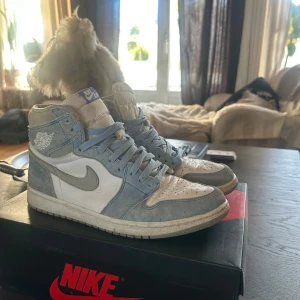 Nike Air Jordan 1 Retro High OG 'University Blue' - Säljer ett par Nike Air Jordan 1 Retro High OG i färgen University Blue. Skorna har en snygg kombination av ljusblå mocka och vitt skinn, med blå snörning och klassisk Jordan-logga på sidan. Ny pris 5499kr