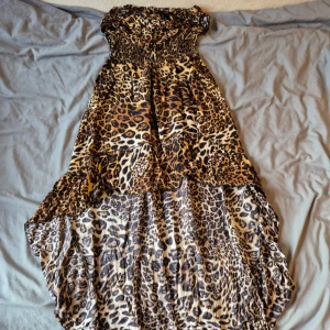 Leopardmönstrad långklänning - Säljer en snygg långklänning med leopardmönster. Klänningen är axelbandslös och har smock upptill för en bekväm passform. Perfekt för en sommardag! 