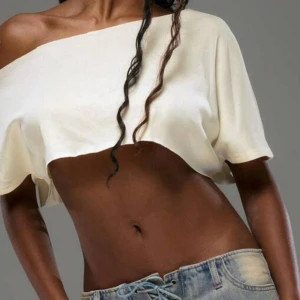 Vit croppad offshoulder topp - Säljer en vit croppad topp med offshoulder-design. Toppen har en lös passform och är perfekt för varma dagar. Styla med jeans eller kjol för en trendig look.