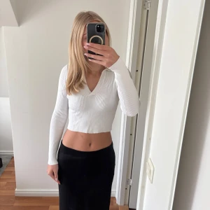 Vit croppad ribbad tröja med v-ringning - Säljer en vit croppad tröja med v-ringning och lång ärm. Tröjan är ribbad och har en tight passform, perfekt för en stilren och enkel look. Passar till mycket och är superbekväm.
