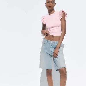 Rosa topp med volangärmar från Zara - Säljer en ljusrosa topp från Zara med volangdetaljer på axlarna. Toppen är ribbad och har en tight passform med rund halsringning. Perfekt för dig som gillar feminina detaljer och en trendig look.