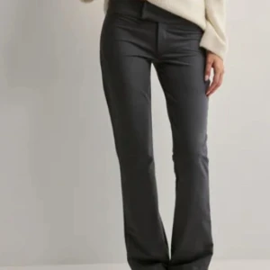 Gråa bootcut kostymbyxor  - Snygga svarta bootcut byxor och låg midja. Byxorna har en figurnära passform upptill och utsvängda ben. Perfekta för en trendig och stilren look.