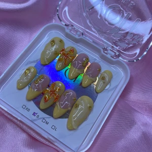 MangoMelt (S);Medium Almond - Säljer ett set med handgjorda lösnaglar i medium mandelform. Naglarna har en mix av pastellgul och nude bas, dekorerade med guldglitter och 3D-blommor i orange och gult. Perfekt för dig som vill ha unika och färgglada naglar. I storlek S: 15 mm, 11,5 mm, 12 mm, 11 mm, 9 mm 