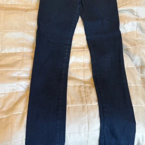 Mörkblå jeansbyxor från Fornarina - Säljer ett par mörkblå jeans från Fornarina med klassisk femficksdesign och kontrastsömmar. Byxorna är skinny jeans och är tillverkade i bomull med lite stretch för extra komfort. Perfekta till många olika outfits! Midja ca 35 cm. Storlek 27. Beninnerlängd ca 77,5 cm. Vid foten ca 14 cm bred 