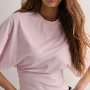 Ljusrosa t-shirt med vida ärmar från NELLY - Säljer en ljusrosa t-shirt med rund hals och korta, vida ärmar. Toppen har en enkel och stilren design i mjukt material, perfekt för en avslappnad look. Från NELLY i storlek xxs❤️