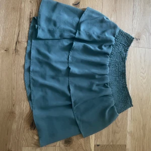 Mörkgrön kjol - Supersöt grön kortkjol. Kjolen har en lätt volang och är perfekt att styla med en enkel topp eller hoodie.