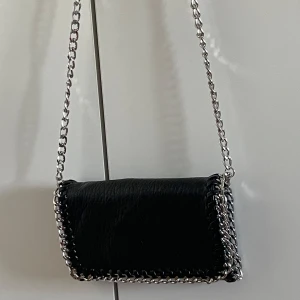 Svart axelväska med kedja från Tiamo - Säljer en svart axelväska från Tiamo som aldrig är använd!!💘