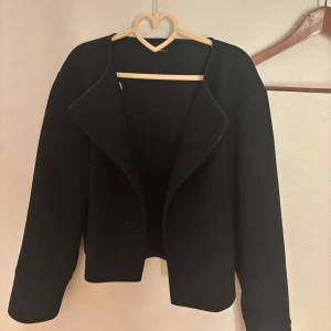 Svart kappa från Gina Tricot - Säljer en svart kappa från Gina Tricot i storlek XS. Jackan har en enkel knappdetalj. knappt använd. 