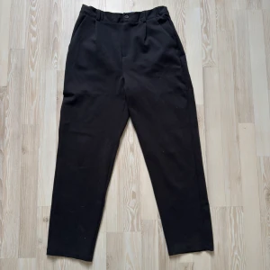 Svarta kostymbyxor från United Colors of Benetton - Säljer ett par klassiska svarta italienska  kostymbyxor från Benetton eftersom dom är för små. Byxorna har knapp och dragkedja framtill och är raka. Dom är i Viskos, storlek 3XL (Barn), 168-172cm. Dom är knappt använda, nästan som nya. Nypris: 500kr