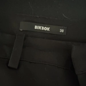  lågmidjade kostymbyxor me slits från BikBok - Svarta kostymbyxor me slits vid fötterna från BikBok i storlek 38. Aldrig använt