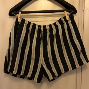 Svartvita badshorts  - Snygga badshorts med svart och vit randigt mönster. Perfekta för sommaren och har en bakficka med knapp. Lätta och bekväma att bära.