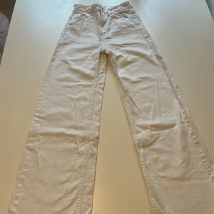 Vita vida jeansbyxor - Säljer ett par vita jeansbyxor i vid modell från H&M. Byxorna har klassisk femficksdesign och stängs med dragkedja och knapp. Perfekta att styla med en enkel topp eller hoodie.