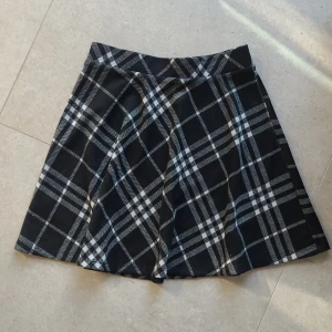 Svart och vit rutig kjol - Säljer en svart och vit rutig kjol från FB Sister. Kjolen har A-linjeformad siluett och klassiskt rutigt mönster. Perfekt att styla med en enkel topp eller stickad tröja. Midjemodell och mjukt material.