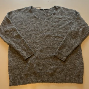 Grå stickad tröja från Lager157 - Mysig grå stickad tröja från Lager157 med v-ringning och långa ärmar. Perfekt för lager-på-lager och passar till både jeans och kjol. Ribbstickade muddar vid ärmslut och nederkant ger en snygg detalj.