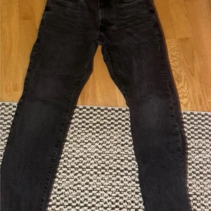 Svarta jeans med regular fit - Säljer ett par svarta jeans med regular fit. Klassisk femficksmodell med raka ben och normal passform. Perfekta till vardags och passar till det mesta. Jeansen har dragkedja och knapp i gylfen.