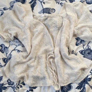 Vit spetsblus med puffärm från MNG - Säljer en romantisk vit blus från MNG med vackra spetsdetaljer och puffiga korta ärmar. Blusen har knytning i midjan och ett feminint, luftigt fall. Perfekt för dig som gillar en söt och trendig stil. Även perfekt för sommar. 