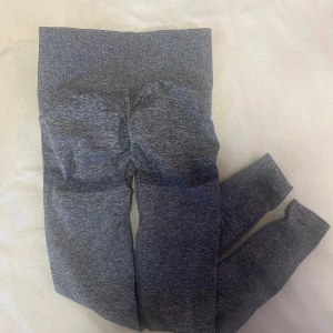 Grå sömlösa tights - Säljer ett par grå sömlösa tights med hög midja. De är stretchiga och sitter tight, perfekta för träning eller gym. Materialet är mjukt och följsamt, vilket ger en bekväm känsla hela dagen Bbl känsla med ribbning.