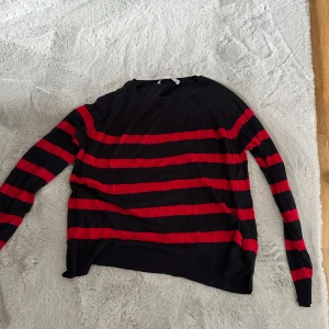 Svart och röd randig tröja från Zara - Säljer en svart långärmad tröja från Zara med breda röda ränder. Tröjan har en avslappnad passform och är perfekt för dig som gillar en enkel men ändå snygg stil.