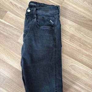 Svarta Replay Anbass - Säljer ett par svarta Replay jeans med snygg tvätt och design. Bra skick och storlek 27 passar. Hör gärna av er vid frågor eller funderingar.