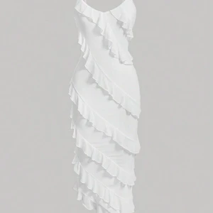 Vit volangklänning med smala axelband - Säljer en vit klänning med smala axelband och flera volangdetaljer som löper diagonalt över hela klänningen. Perfekt för dig som vill ha en romantisk och trendig look.