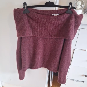 Vinröd offshoulder stickad tröja - Mysig vinröd stickad tröja med offshoulder-design. Perfekt för kyliga dagar och ger en avslappnad men trendig look. Tröjan har långa ärmar och bred krage som vilar över axlarna. Är i storlek dam S men är väldigt stor i storleken, skulle säga att det är en M eller L!