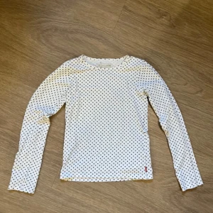 Vit långärmad tröja - Säljer en vit långärmad tröja med små svarta prickar. Tröjan har en rund halsringning och är i ett mjukt bomullsmaterial.🩷