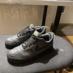 Nike Air Force 1 i mörkgrått med neongula detaljer - Säljer ett par mörkgrå Nike Air Force 1s