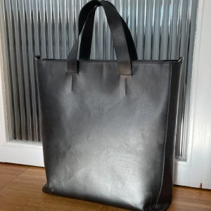 Totebag-reseväska - Stor och rymlig totebag av vegan leather. Den har några vita defekter på kanterna som inte syns särkilt tydligt. Mått: höjd 40cm, bredd 35 cm, djup 12 cm 