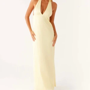 Peppermayo klänning - Säljer en elegant ljus långklänning med djup v-ringning och halterneck. Klänningen har en stilren och minimalistisk design, perfekt för sommarens tillfällen. Materialet ger ett mjukt och följsamt fall. Perfekt på bal eller bröllop 